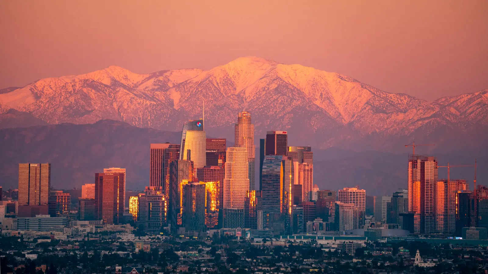 Downtown Los Angeles skyline at dusk with the San Gabriel Mountains behind
