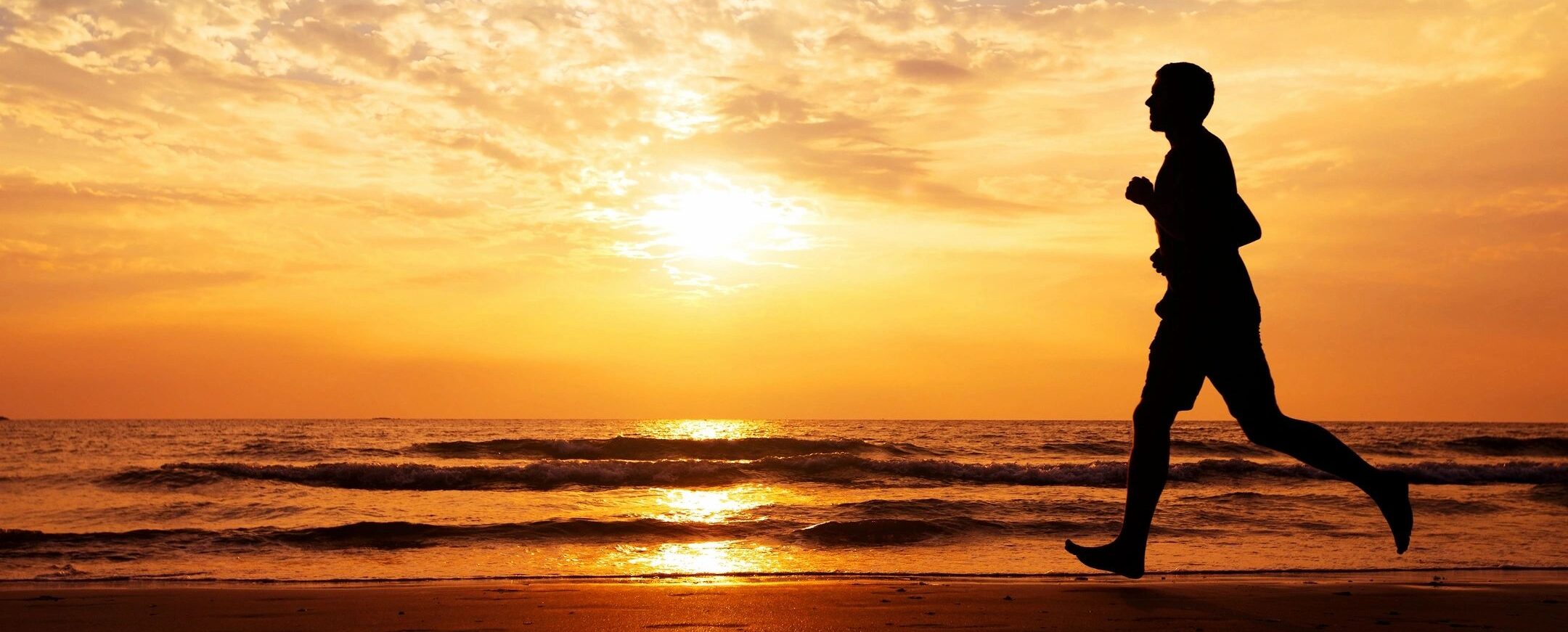 Man running along a serene beach at sunset, embodying vitality and the journey to recovery.